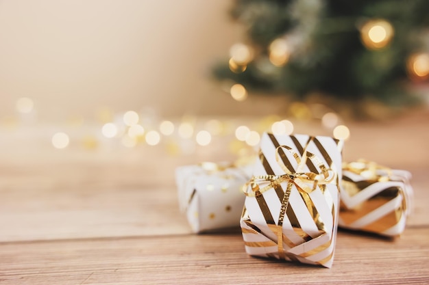 Фото Белые подарочные коробки, перевязанные золотыми лентами и бантом на деревянном фоне. интернет-магазины и продажи рождественских открыток с рождеством и новым годом.