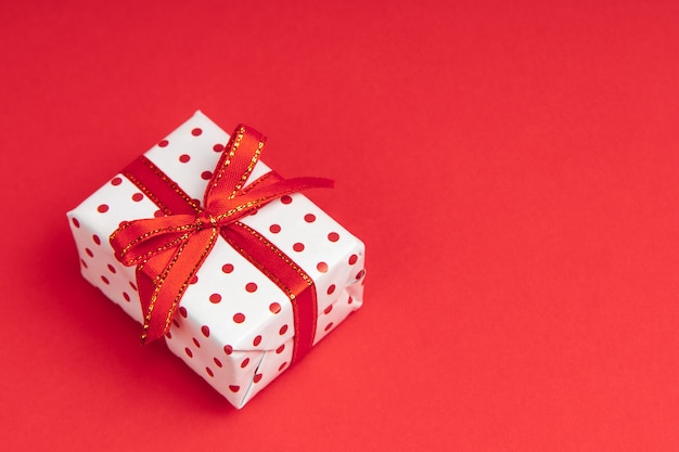 White gift wrapped in gift paper polka with festive ribbon on red