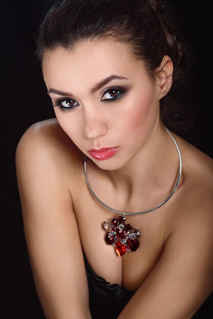 White girl brunette beauty portrait on black background with jewelry