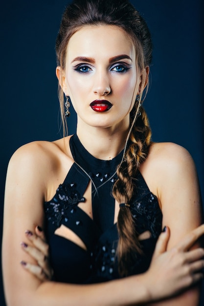 White girl modell on a dark background in a dress made of cut stripes of black fabric