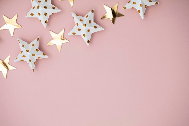 White and gold star decorations on a pastel pink Seasonal festive background