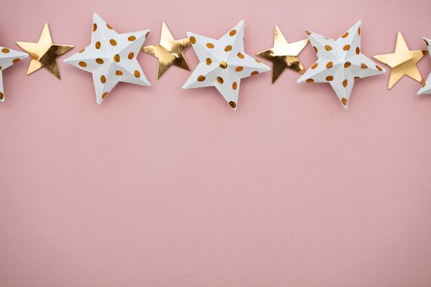 White and gold star decorations on a pastel pink Seasonal festive background