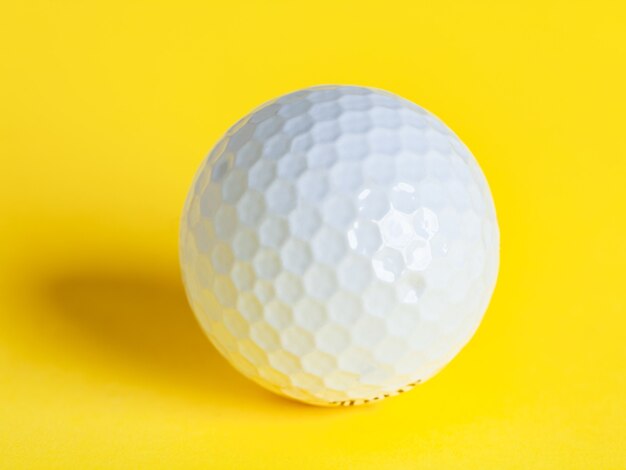 A white golf ball isolated on yellow, sport