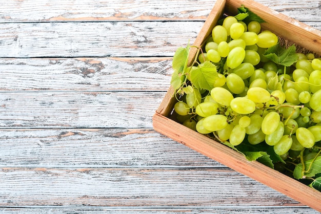 White Grapes in a wooden box on a white wooden table Leaves of grapes Top view Free space for text