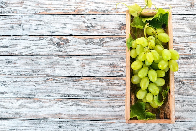White Grapes in a wooden box on a white wooden table Leaves of grapes Top view Free space for text