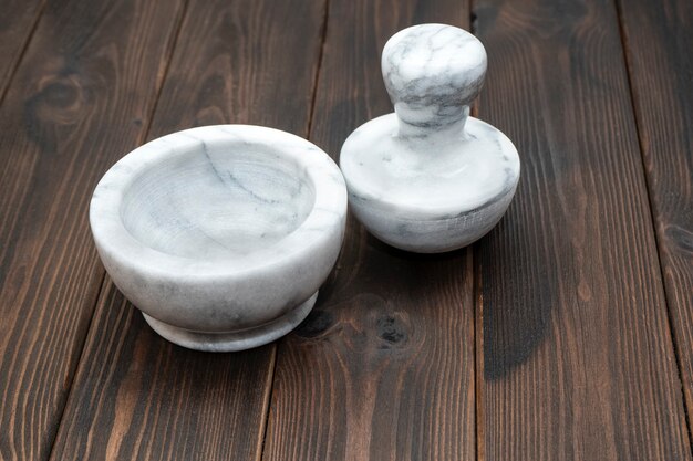 暗い木製のテーブルの上の白と灰色の大理石の乳鉢と乳棒