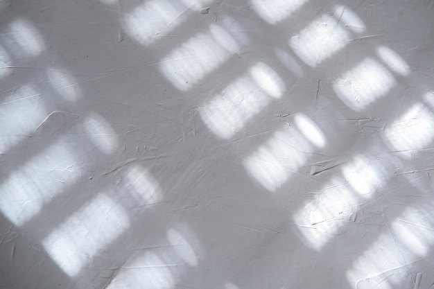 写真 白灰色の漆喰壁の背景。白いコンクリートの背景をクローズアップ。影と太陽の光線の研磨白色セメントの背景