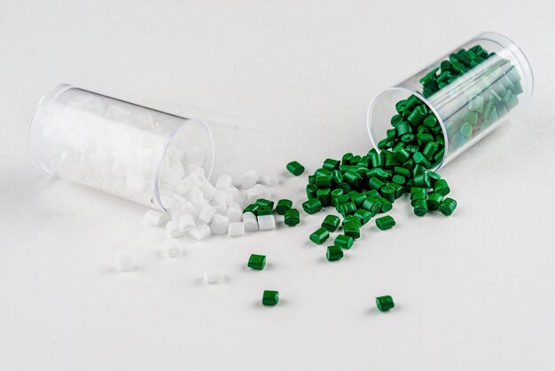 Photo white and green plastic dye in granules in test tubes isolated on a white background