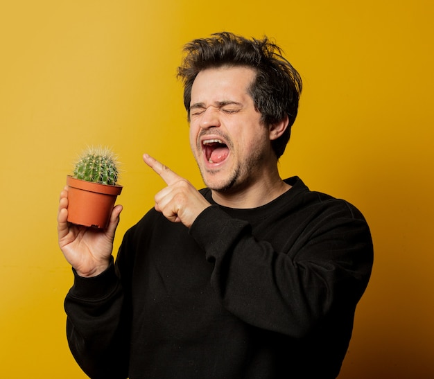 White guy in blakc clothes hold cactus