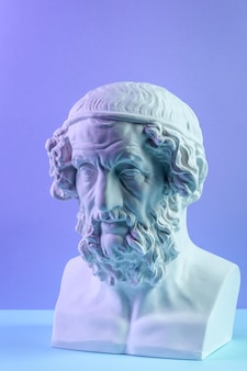 Copia in gesso bianco dell'antica statua della testa di omero per artisti su sfondo blu. scultura in gesso del volto dell'uomo.