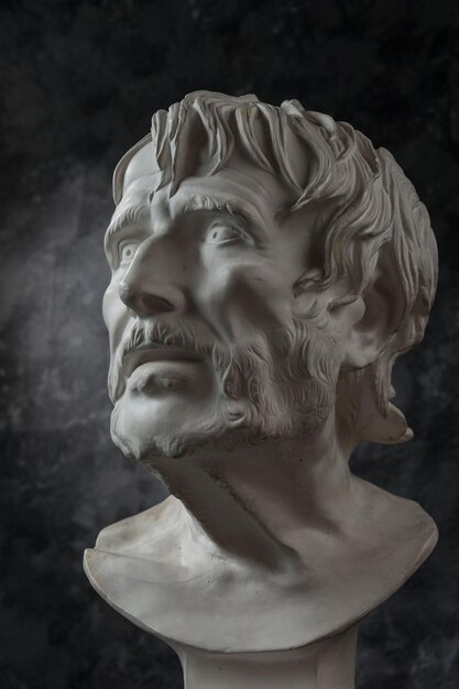 White gypsum copy of ancient statue of Lucius Seneca head for artists on a dark textured background. Seneca 4 BC-65 AD Roman stoic philosopher, statesman and tutor to the future Emperor Nero.