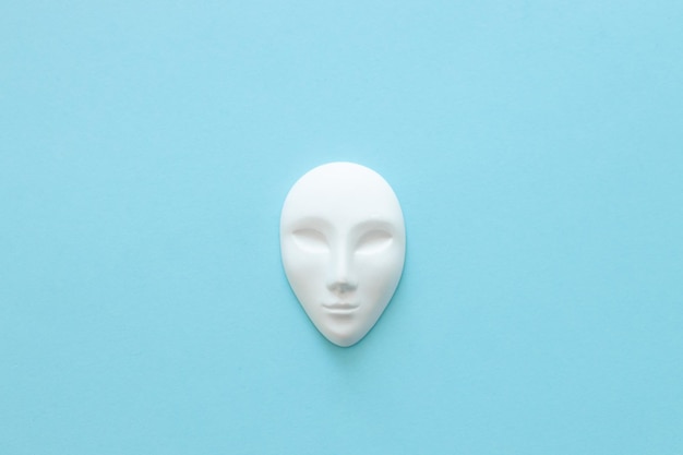 White gypsum mask of human with closed eyes on blue background