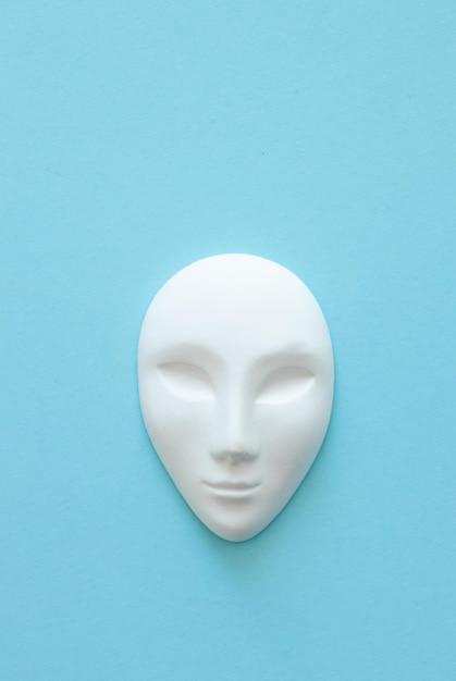 Белая гипсовая маска человека с закрытыми глазами на синем фоне