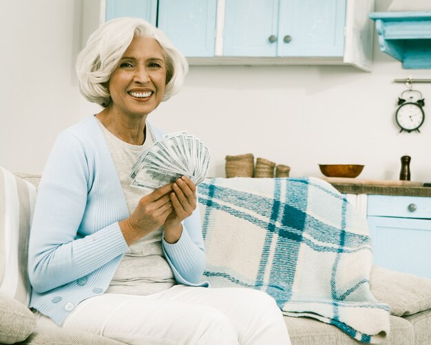 White haired senior woman holding money