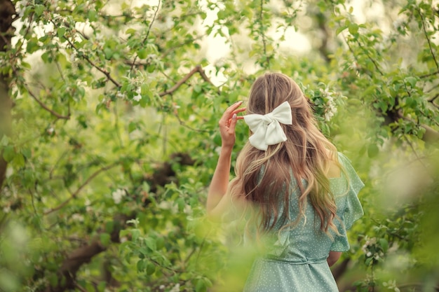 White hairpin bow on women's hair back view in blooming garden