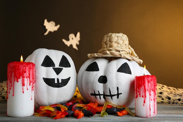 Фото Белые тыквы хэллоуина и свечи на деревянном столе на фоне темного цвета