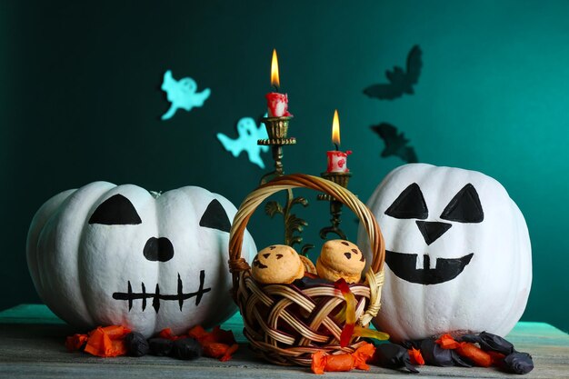 white halloween pumpkins candies and candles on wooden table on dark color background