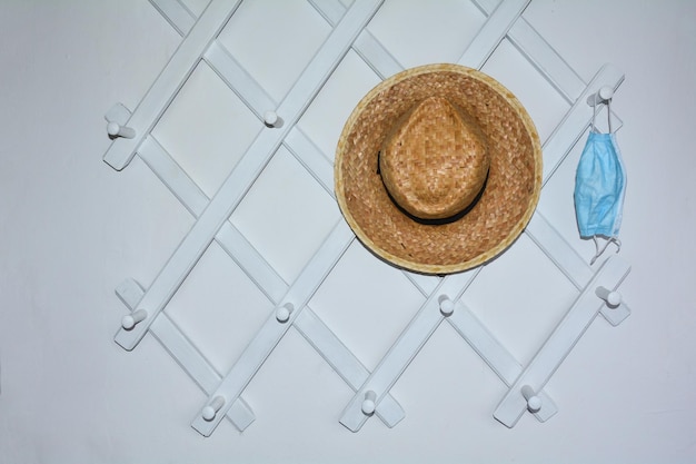 Photo white hallway cloakroom with a hung respirator and a straw hat on the right