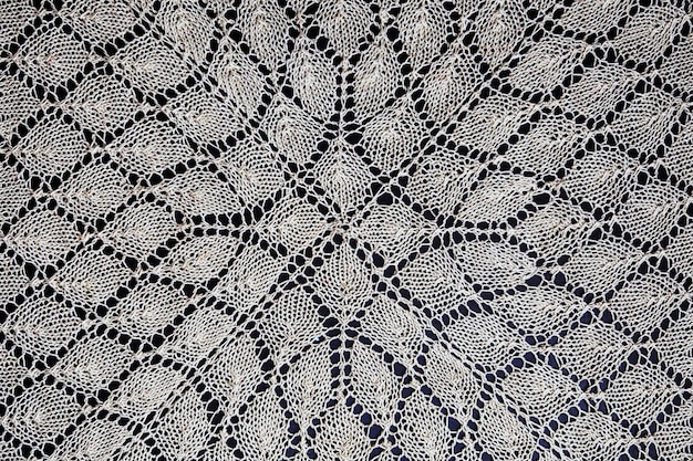 Photo white hand knitted lace on black surface.