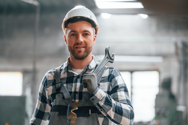 Foto in cappello duro bianco il lavoratore maschio della fabbrica in uniforme è all'interno