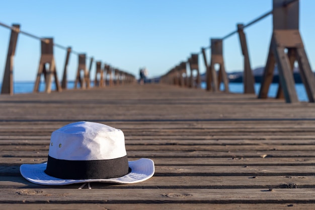 Un cappello bianco con una fascia nera che giace a terra su un molo su una spiaggia spagnola