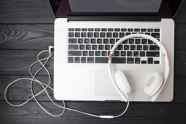 Photo white headphone and laptop computer on wooden background.