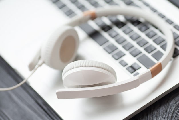 White headphone and laptop computer on wooden background.