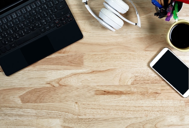 White headphones and keyboard on the wooden working table