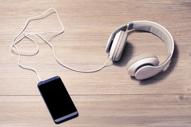 White headphones and mobile phone on a table