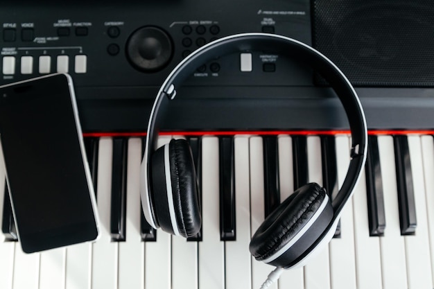 White headphones and smartphone on musical synthesizer keyboard Headphones on electronic piano Top view