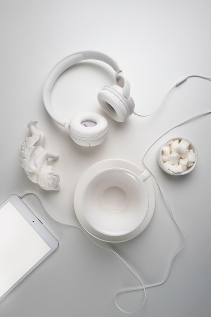 Photo white headphones and a white cup on a white table