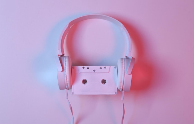 White Headphones with audio cassette in pinkblue neon gradient light Minimalism music concept