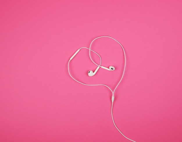 White headphones with a cable on pink 