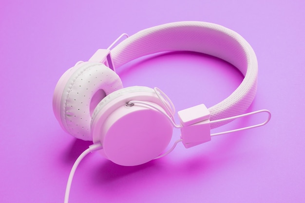 White headphones with cord on an empty purple background