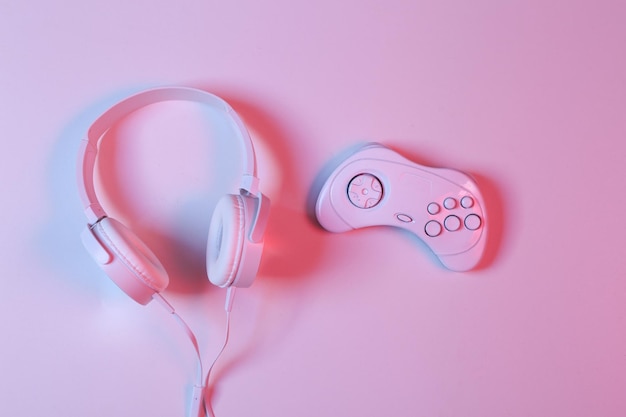 White Headphones with gamepad in pinkblue neon gradient light Minimalism gaming concept