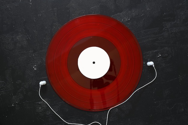 검은색 배경에 와이어와 빨간색 비닐 디스크가 있는 색 헤드폰 음악을 재생하는 레트로 기법