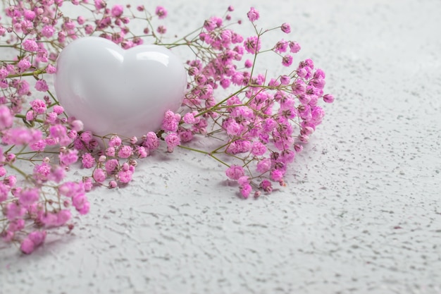 Un cuore bianco su uno sfondo di fiori rosa ha un posto per il testo.