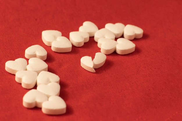 White heart shaped pills on a red background