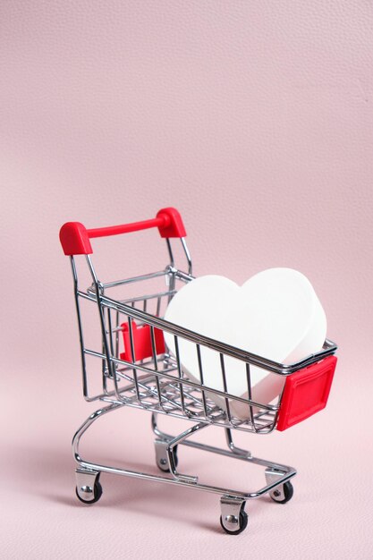 White heart in a shopping basket on a pink background