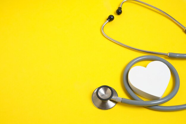 White heart and stethoscope on yellow backgroundheart disease medical examination