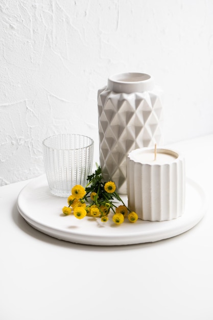 Photo white home decoration with yellow flowers ceramic vase candle and glass on tray