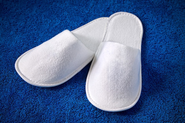 White home slippers lying on blue rug