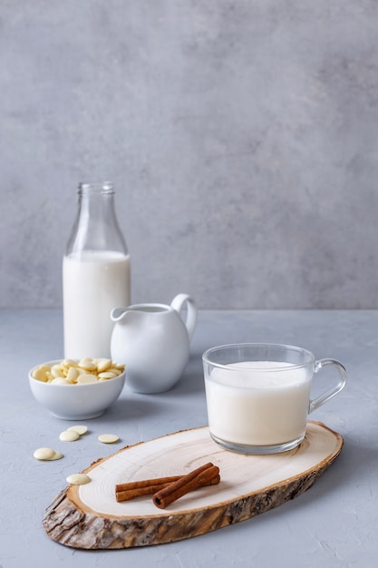 White hot chocolate and cinnamon on a wooden stand on a gray surface. Healthy breakfast concept. Keto drinks. Copy space.