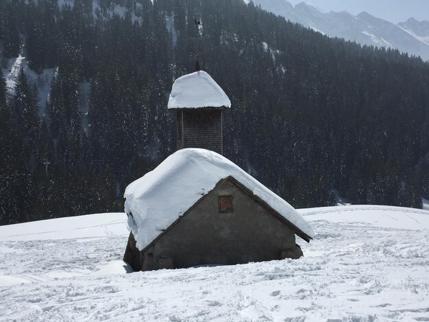 White house on snow covered land and trees against mountain