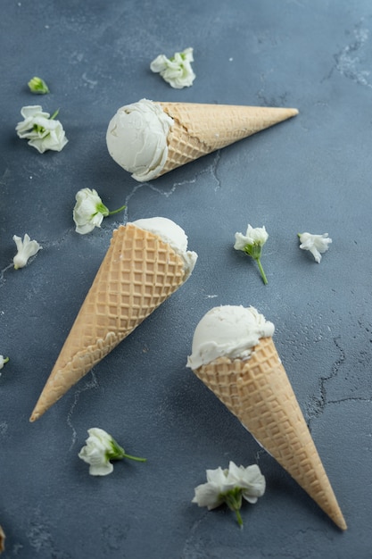 White hyacinth and vanilla ice cream in waffle cones on blue background. Pattern concept