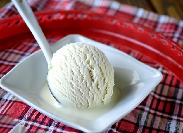 White ice cream scoop in a bowl with red syrup and a spoon ai generated