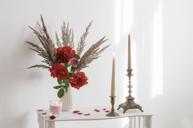 White interior with bouquet of roses and burning candles