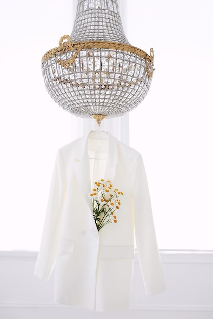 white jacket on hanger with bouquet of daisies on the chandelier