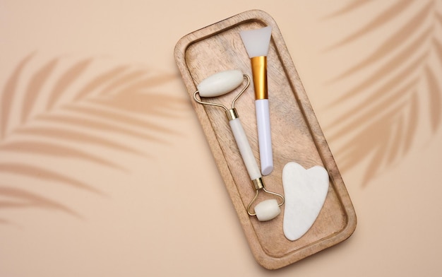 Photo white jade gouache massager and massage jade roller on a beige background