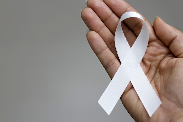 Photo white january, mental health awareness campaign. person holding a white ribbon.